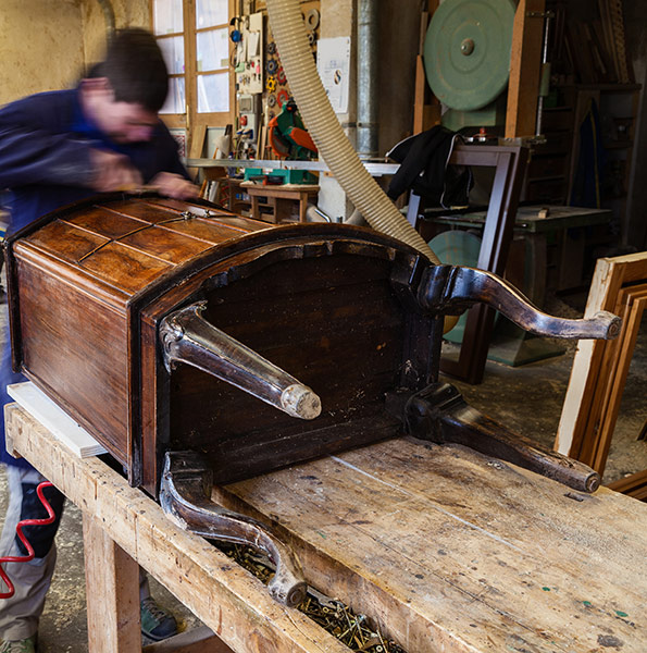 Craftsman working in workshop on antique furniture piece